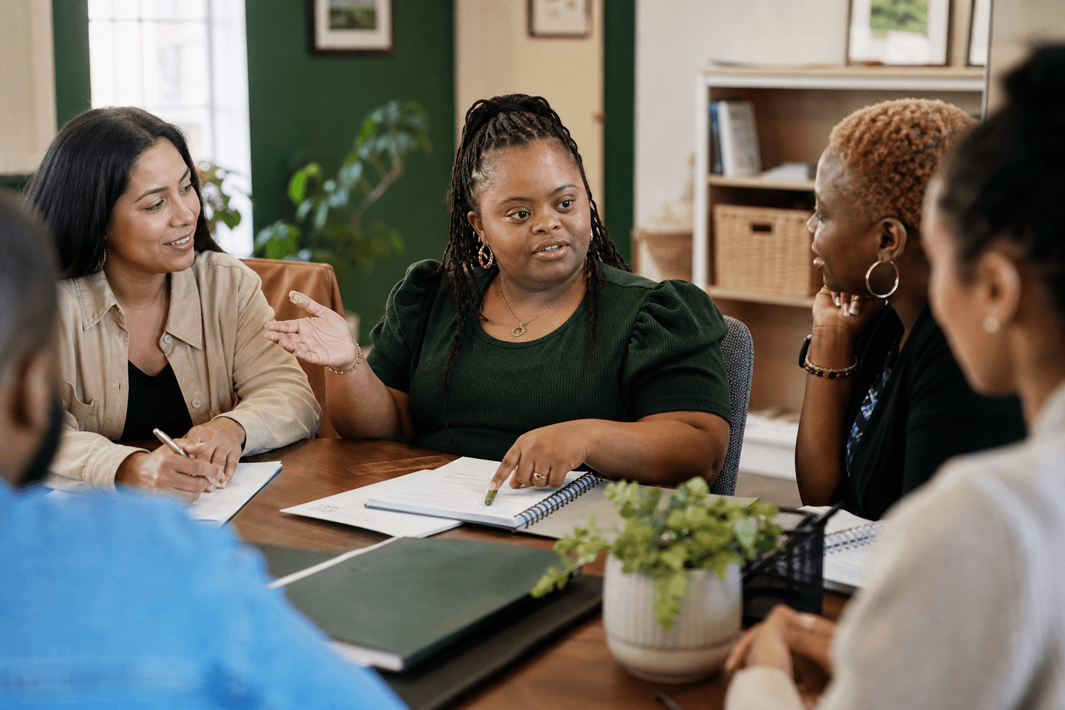 A Black woman with Down syndrome leads her planning meeting while her support team listens.